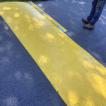 Bright yellow speed bump painted by Davis Line Striping in Pottstown, PA to improve driver awareness and safety. Freshly painted yellow speed bump on asphalt in Pottstown, PA