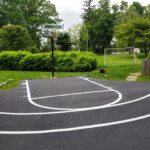 Custom basketball court striping completed in a large backyard by Davis Line Striping. Backyard basketball court with curved arc and painted key