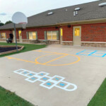 Colorful playground court with custom basketball, hopscotch, and four square striping by Davis Line Striping. Playground game court with basketball, hopscotch, and four square striping