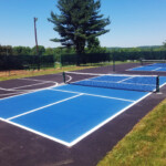 Bright blue pickleball courts with adjacent basketball markings striped by Davis Line Striping. Fresh blue pickleball courts and basketball striping at a recreational facility